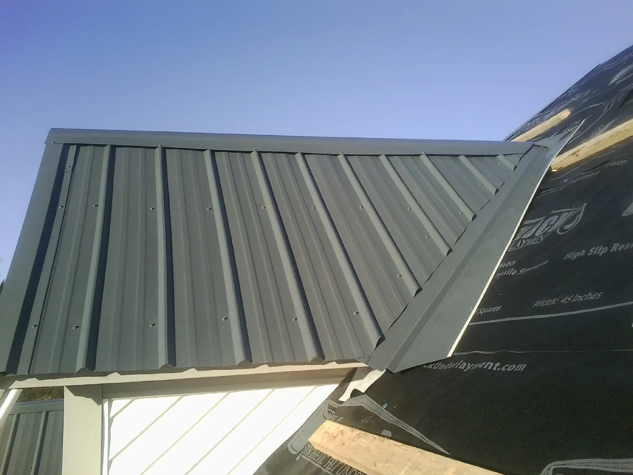 Gray metal roof panels going on over a garage gable in Pearl