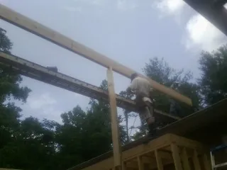 Carpenter setting a ridge beam over a new addition frame — Ice Dam Removal by Roofing Brothers in Pearl