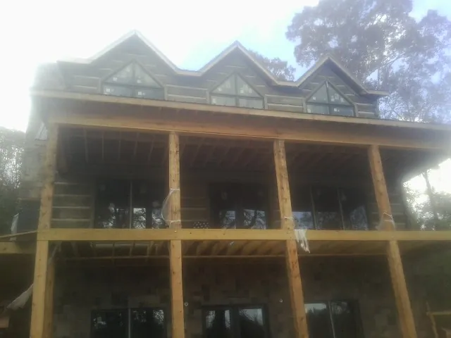 Dormers and porch framing on a large log home under construction — Roof Coating work by our crew in Pearl