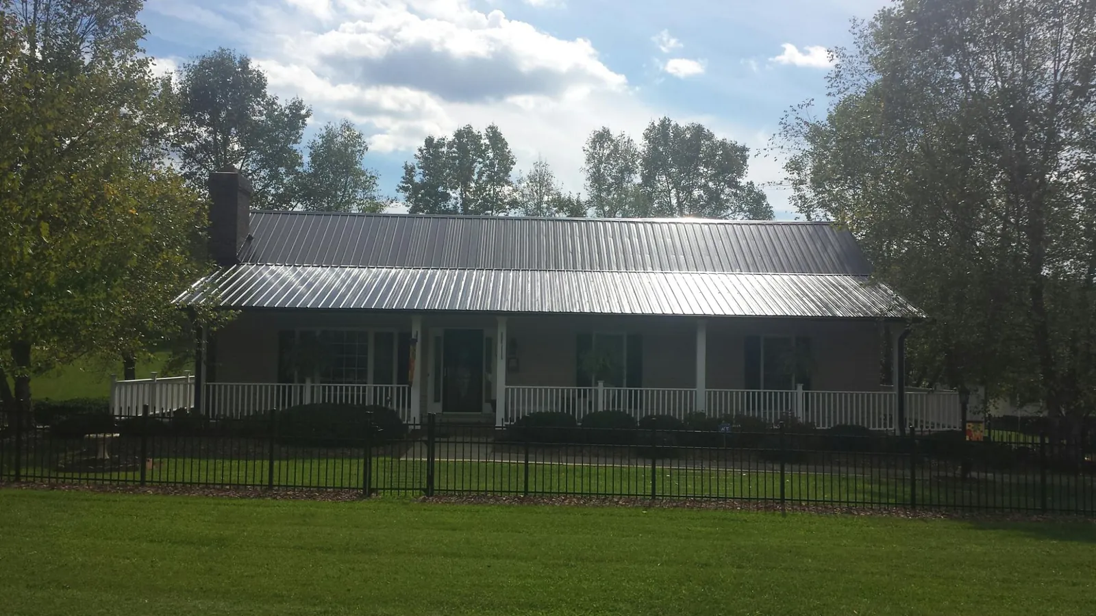 Gray metal roof on a brick ranch with a full width front porch — Gutter Guard Installation work by our crew in Pearl