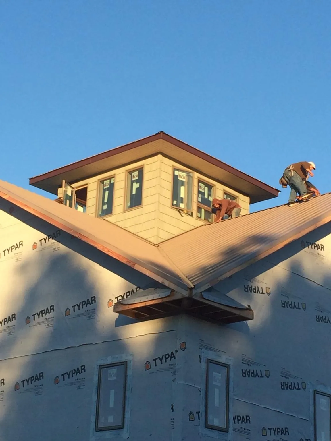 Roofers working around a rooftop cupola on a new metal roof at sunset — Roof Waterproofing in Pearl by Roofing Brothers